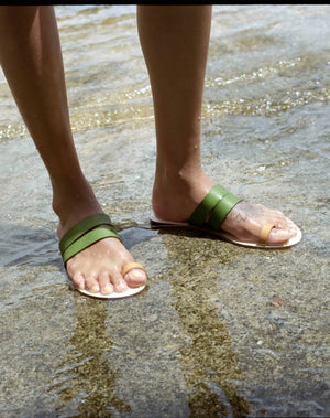 green leather sandals, handmade in Greece, model standing in mediterranean sea
