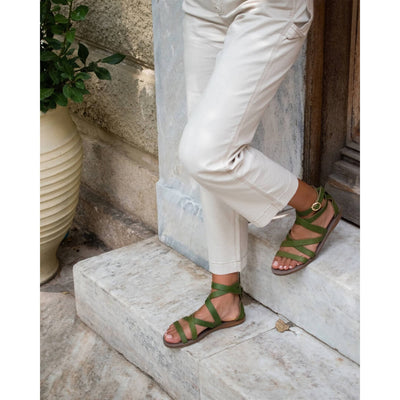 woman wearing greek gladiator sandals in olive green Italian leather #color_moss-green